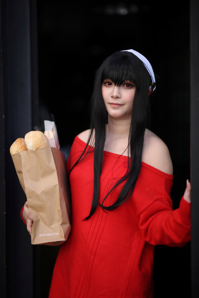 一个漂亮的年轻女人的肖像，穿着红毛衣，在走廊的购物袋里装着面包图片下载