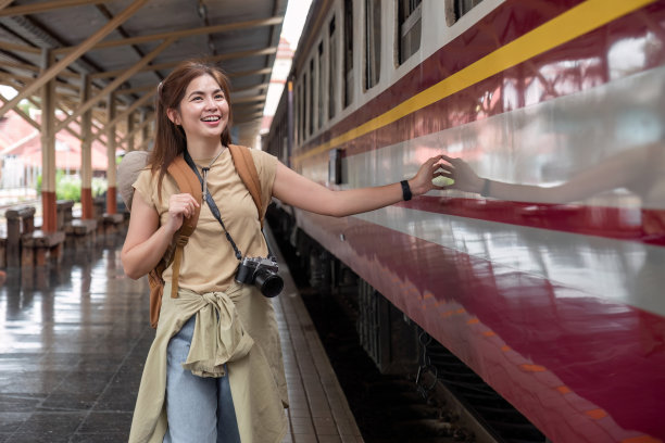 周末旅行的年轻女子背着背包在火车站等火车。图片下载