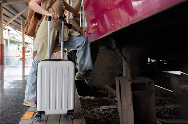 周末旅行时，年轻女子提着行李箱在火车站等火车，特写概念。图片下载