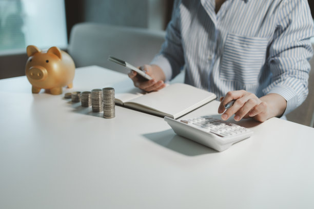 一个企业主正在数钱并在财务账簿上做笔记，金融家正在核实从客户的投资中收到的收入，会计师计算出总共有多少钱。图片下载