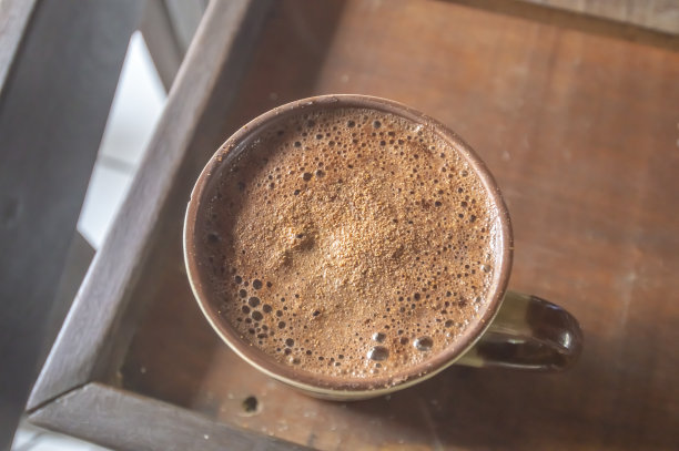 木桌上放着一大杯加卡布奇诺的咖啡，图片俯视图图片下载