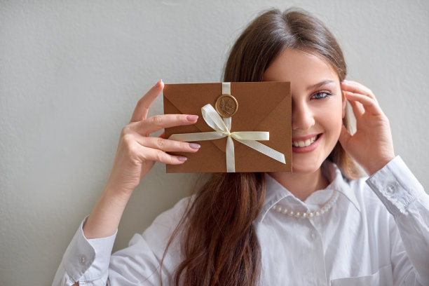 女子手持铜制礼券，有蜡封的请柬信封，婚礼请柬卡片。浅景深水平照片图片下载
