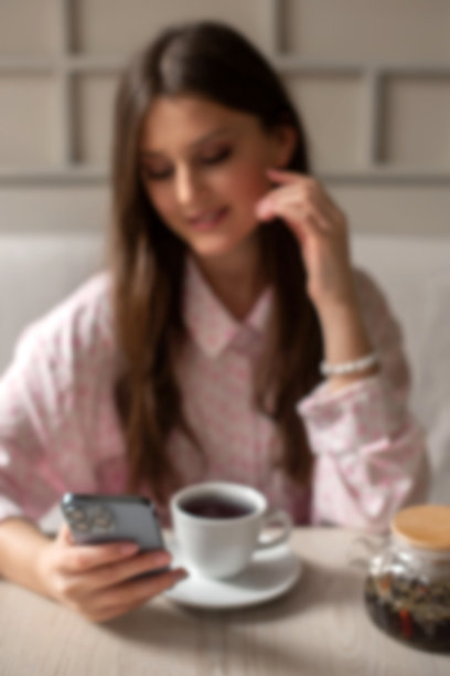 午休时间在咖啡馆喝茶、用手机搜索信息的模糊女性（竖版照片）图片下载
