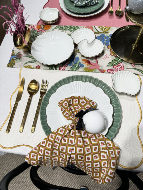 餐桌摆放的特写图片，布制餐垫上的扇形餐盘，有图案的餐巾纸，金色的金属叉子，勺子和刀，桌布，抬高的视图图片下载