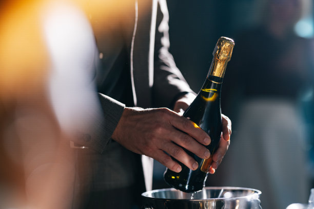 穿着西装的匿名男子拿着一瓶香槟图片下载