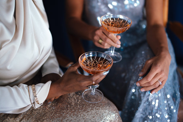 两个穿着派对服装的匿名女人坐在那里拿着饮料图片下载