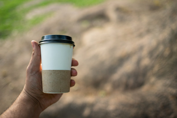 一个人在户外公园拿着咖啡。与Copyspace图片下载