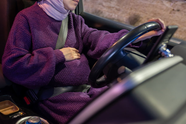怀孕的阿拉伯穆斯林妇女晚上开车，穿着冬衣，戴着头巾，系着安全带，自信地开车，感觉很安全图片下载