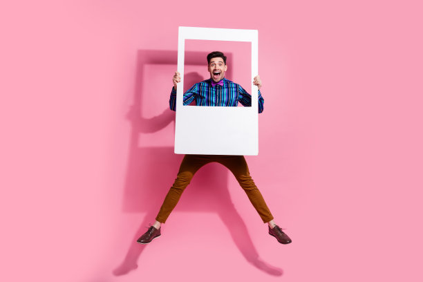 全身大小的照片跳跃疯狂英俊的男朋友拿着纸记忆窗口即时快照孤立的粉红色背景图片下载
