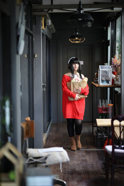 一个漂亮的年轻女人的肖像，穿着红毛衣，在走廊的购物袋里装着面包图片下载