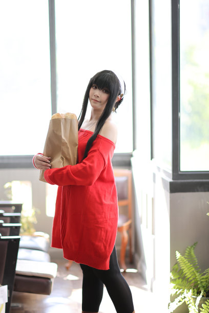 一个漂亮的年轻女人的肖像，穿着红毛衣，在走廊的购物袋里装着面包图片下载