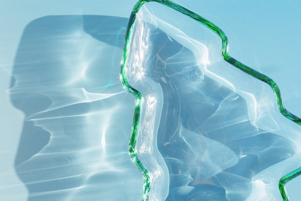 绿色的彩色玻璃板像圣诞树一样，圣诞冷杉在阳光下有美丽的影子，阳光耀眼，蓝色单色闪闪发光。寒假概念，极简抽象美学照片图片下载