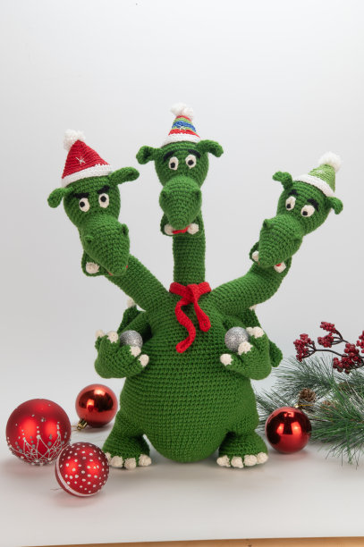 戴年帽的三头龙和绿纱编织的红围巾。龙手里拿着新年的玩具图片下载