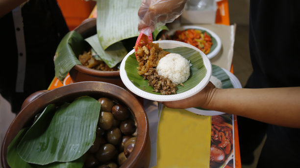 一个男人的特写照片，为顾客提供典型的日惹美食——古德格米饭和配菜图片下载