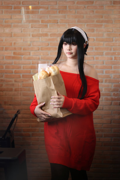 一个漂亮的年轻女人的肖像，穿着红毛衣，在走廊的购物袋里装着面包图片下载