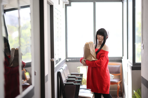 一个漂亮的年轻女人的肖像，穿着红毛衣，在走廊的购物袋里装着面包图片下载