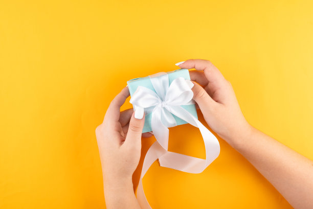 第一人称俯视图照片的女性手拿蓝色礼盒与白色丝带。我的手捧着一个蓝色的礼品盒图片下载