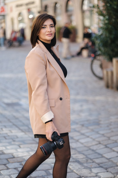 优雅的女摄影师在城市用单反相机的肖像。女人走在城市里拍照片图片下载