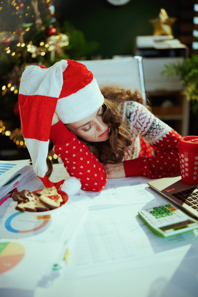 疲倦时髦地睡在有圣诞树的绿色办公室里图片下载