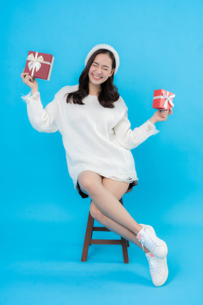 全身照亚洲女子长发，微笑和快乐，拿着礼盒准备新年和圣诞节的庆祝活动，拍摄的蓝屏在演播室。图片下载