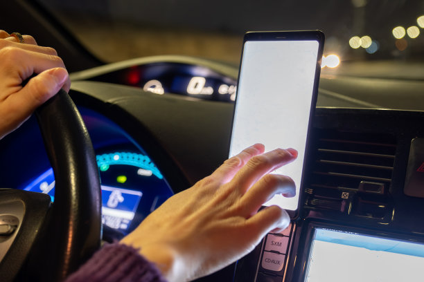 阿拉伯穆斯林妇女晚上开车，穿着冬衣，戴着头巾，系着安全带，自信地开车，通过手机和GPS使用地图图片下载