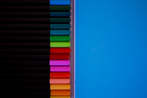 儿童艺术绘画。儿童绘画课程。一组均匀地排列在蓝色背景上的彩色铅笔。彩色铅笔整齐地排成一排。图片下载