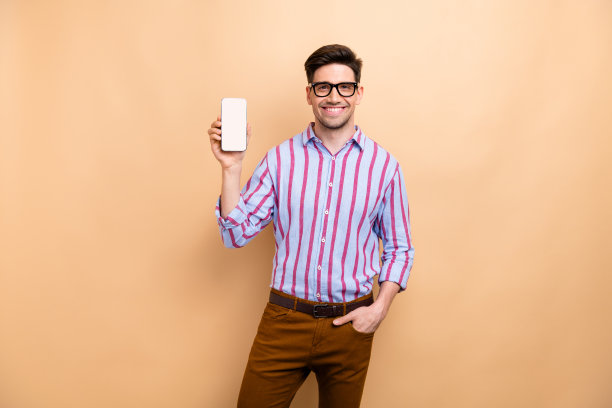 年轻微笑的成功英俊商人拿着智能手机触屏界面，米色背景孤立的照片图片下载