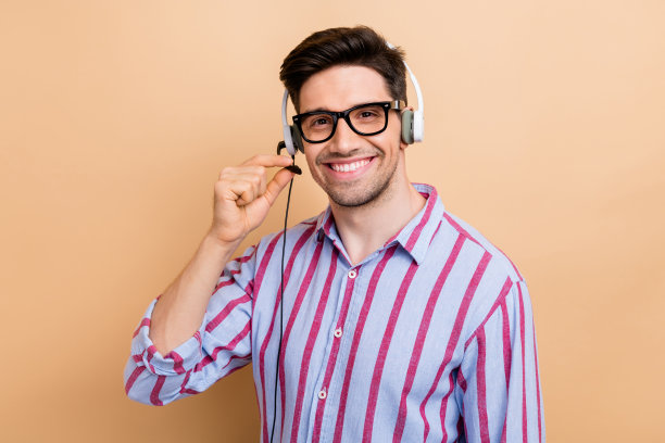 年轻的微笑客户服务支持接线员男子照片的专业呼叫接线员触摸麦克风隔离在米色背景图片下载