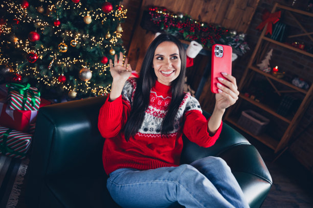 照片肖像迷人的黑发年轻女子视频通话挥手hi装扮装饰毛衣客厅圣诞装饰图片下载