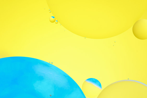微距照片与圆形油滴水面。抽象的蓝色和黄色背景与油泡沫。图片下载