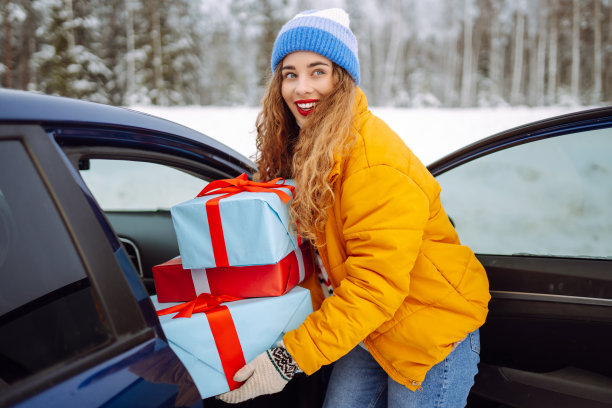 快乐的年轻女子把新年礼物装进车里。图片下载