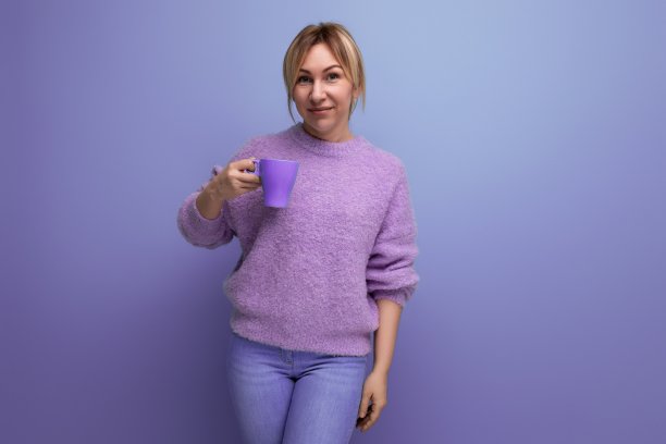 清新的金发年轻的千禧一代女性在休闲的样子与一杯可可明亮的背景与复制空间图片下载