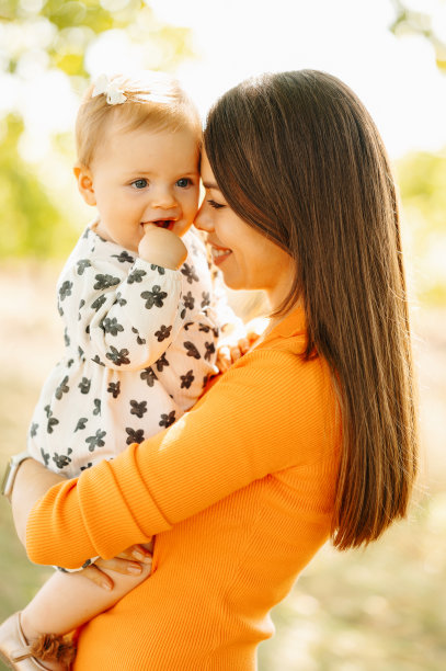 垂直照片的母亲拥抱她的女婴在户外和风扇图片下载
