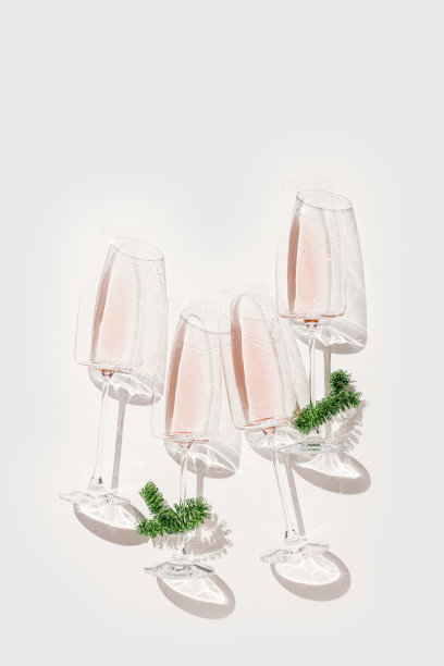 最小的新年公寓躺在香槟杯玫瑰酒，圣诞绿色金属丝作为装饰。假日美学静物照片，俯视图酒杯在阳光，太阳阴影和星星图片下载