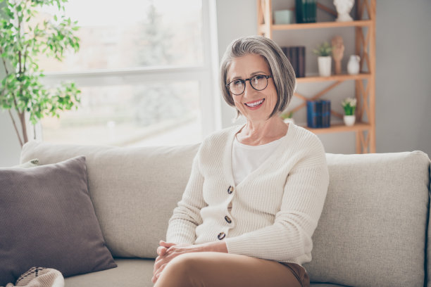照片中美丽开朗的女士穿着时髦的毛衣坐在沙发上独自在家度过周末图片下载