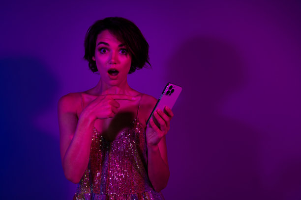 照片惊讶的女士用手机智能设备指向网站新闻假期孤立的霓虹彩色背景图片下载