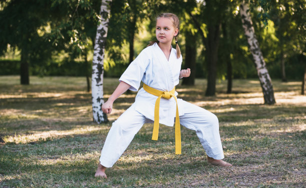 在自然背景下在户外练武术的女孩。穿着白色和服的活跃少年。做运动和锻炼的孩子。战斗的概念。图片下载