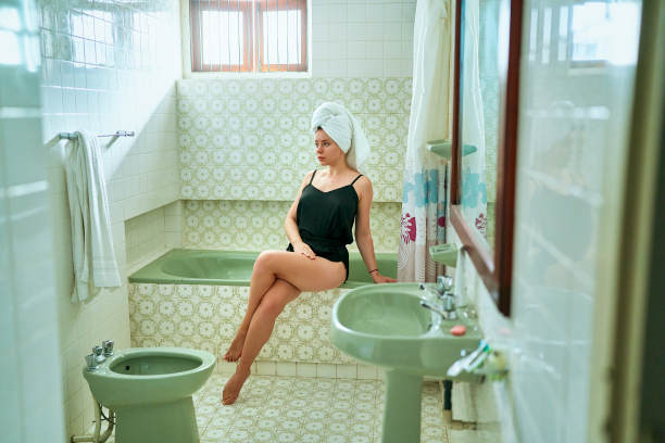 复古风格的浴室场景，女人在爪足浴缸里放松，头上披着毛巾。复古沐浴时光，放松身心，个人护理理念。女性卫生，美容仪式，家庭环境。温泉氛围。图片下载