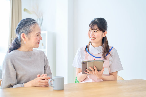 穿围裙的年轻女子和年长女子在家里聊天图片下载
