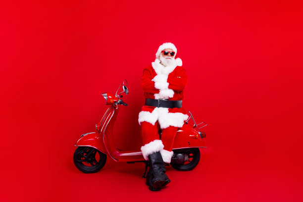 全尺寸照片古怪的老年圣诞老人双手合十坐在自行车新年节日活动孤立的红色背景图片下载
