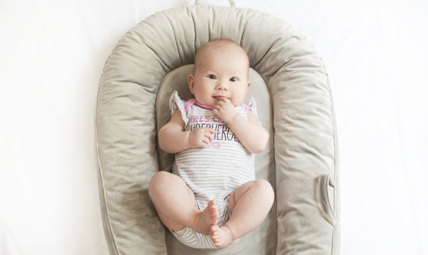 可爱的高加索新生女婴在婴儿窝里玩她的脚。婴儿的里程碑图片下载