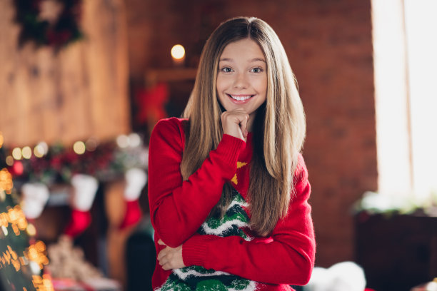 迷人的年轻少女的肖像照片微笑着触摸下巴在冬天穿着红色的套头衫呆在家里在寒冷的天气户外图片下载