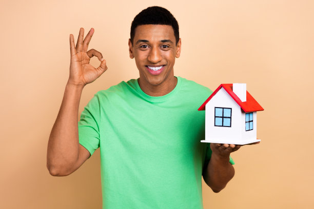 迷人的年轻人的照片肖像显示ok的标志洞小房子穿着时尚的绿色衣服孤立在米色背景图片下载