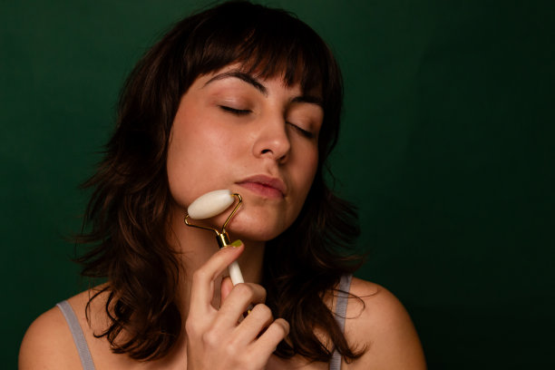 漂亮的黑发女人用玉辊刮脸图片下载