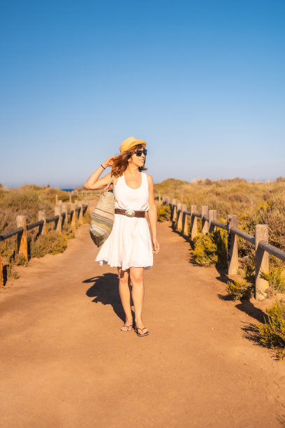 一个女人拿着沙滩包走路的垂直照片图片下载