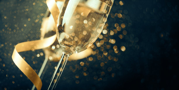 两个香槟酒杯，金色缎带和金色闪光的黑色背景图片下载