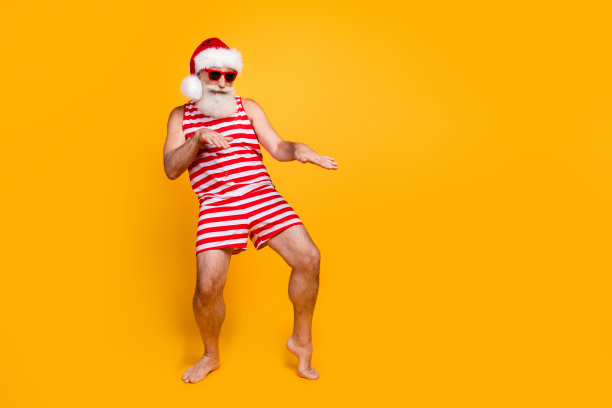 正面开朗的资深男子圣诞泳装帽享受迪斯科舞厅空的空间孤立的黄色背景的全身照片图片下载