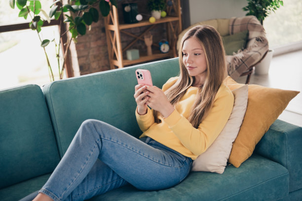 躺在舒适柔软的沙发上的可爱女孩的全身照片，在寒假期间在家上网社交媒体网络图片下载