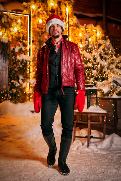 装扮成圣诞老人的男人在装饰着花环的街道上摆姿势，新年和圣诞节的概念图片下载