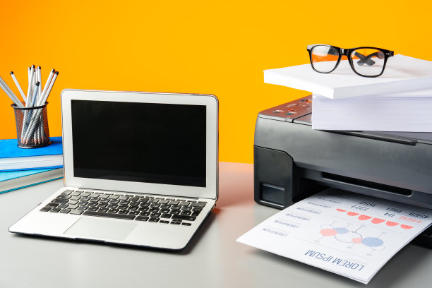 桌子上的激光打印机和笔记本电脑，黄色背景图片下载